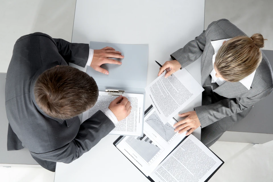 Deux professionnels en costume examinent des documents contractuels dans un bureau moderne